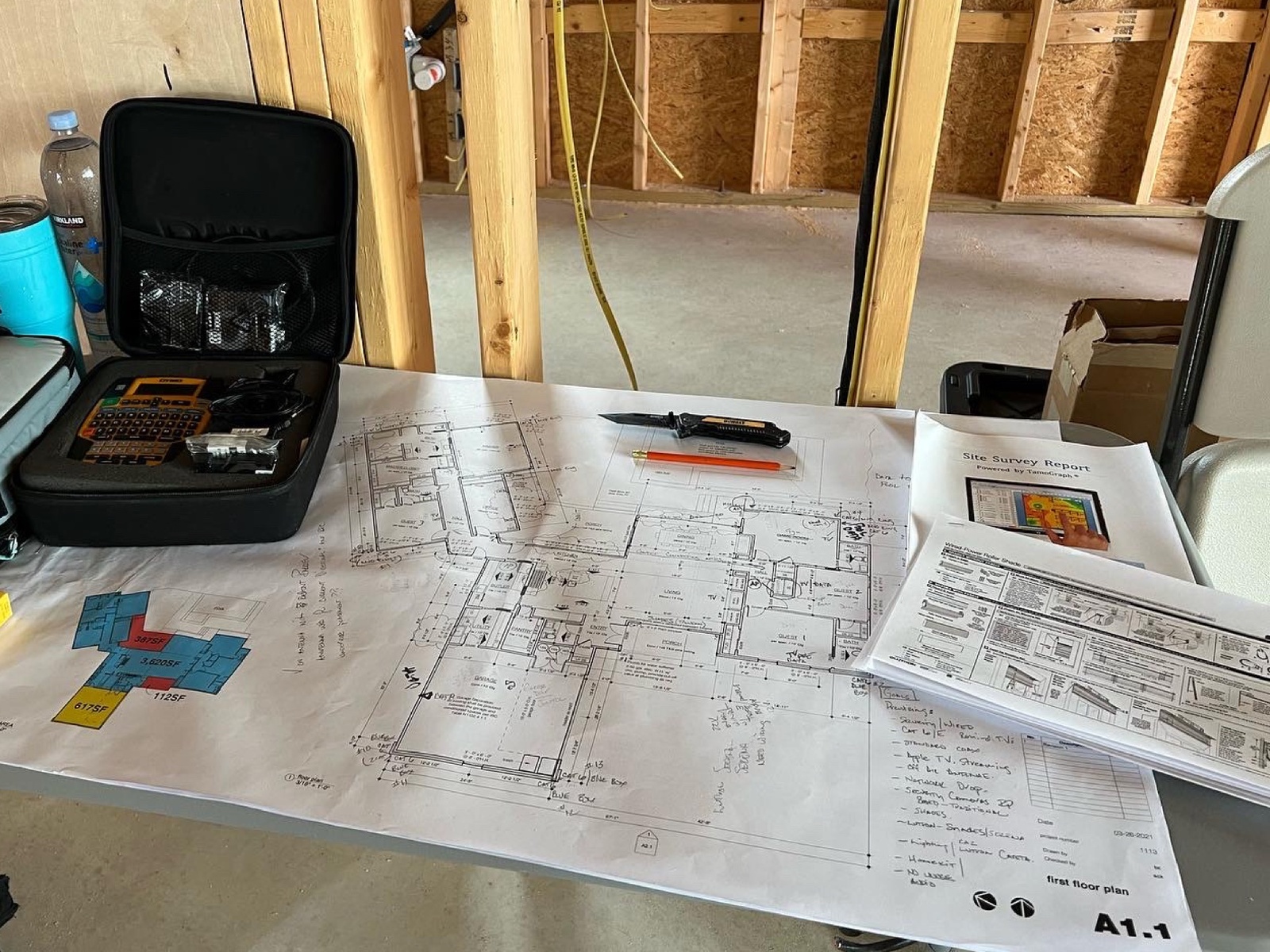 Annotated floor plan and Wi-Fi site survey laid out on a work table inside a framed new build