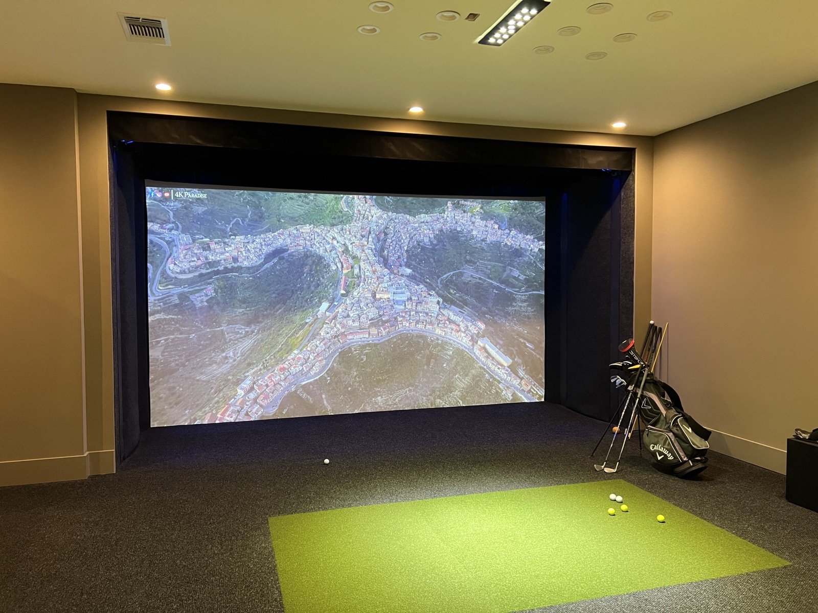 Multi-use home theater with a golf simulator sharing the projection screen
