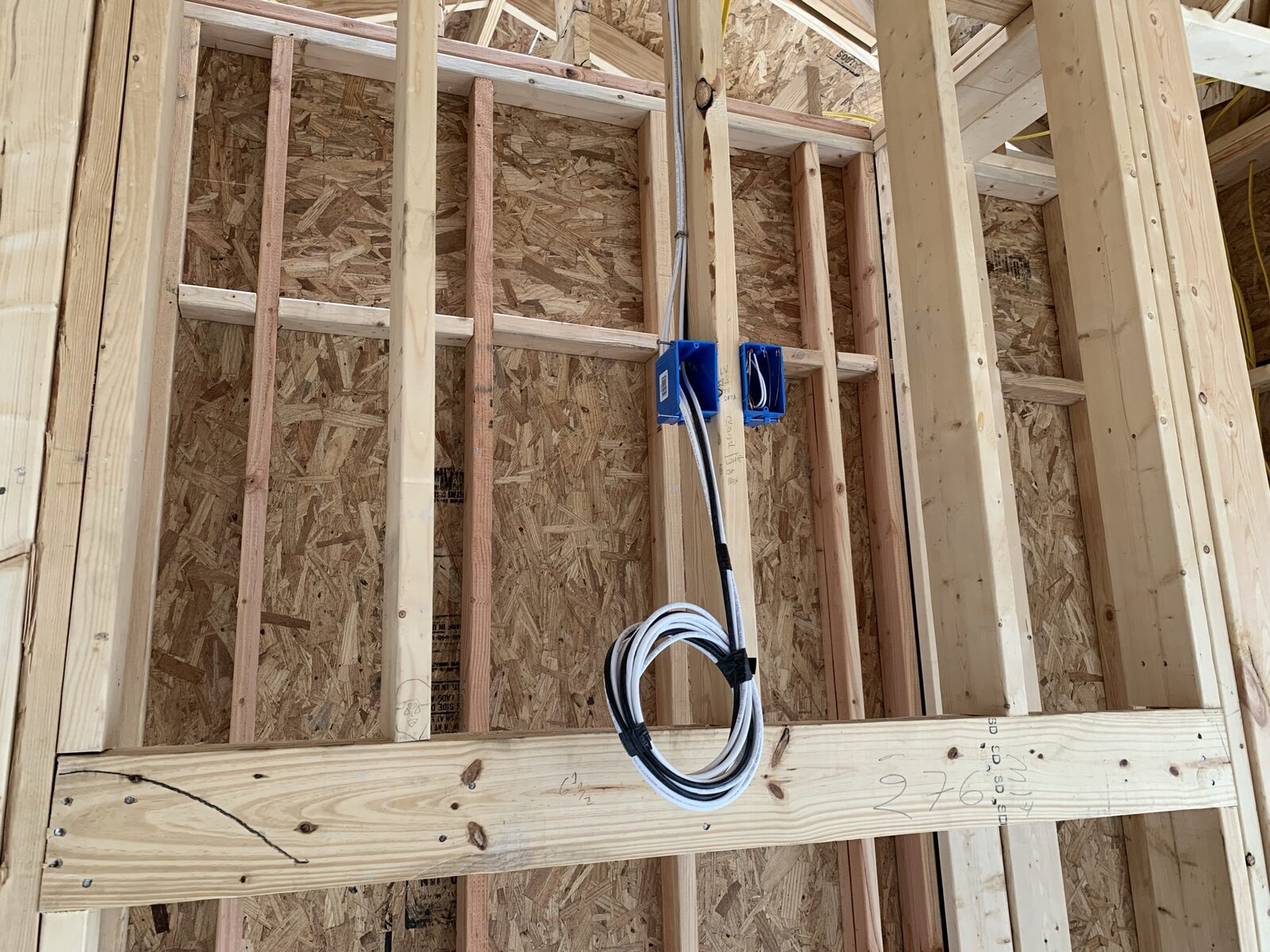 Network cable coiled and secured at a low-voltage box in the framing of a new build