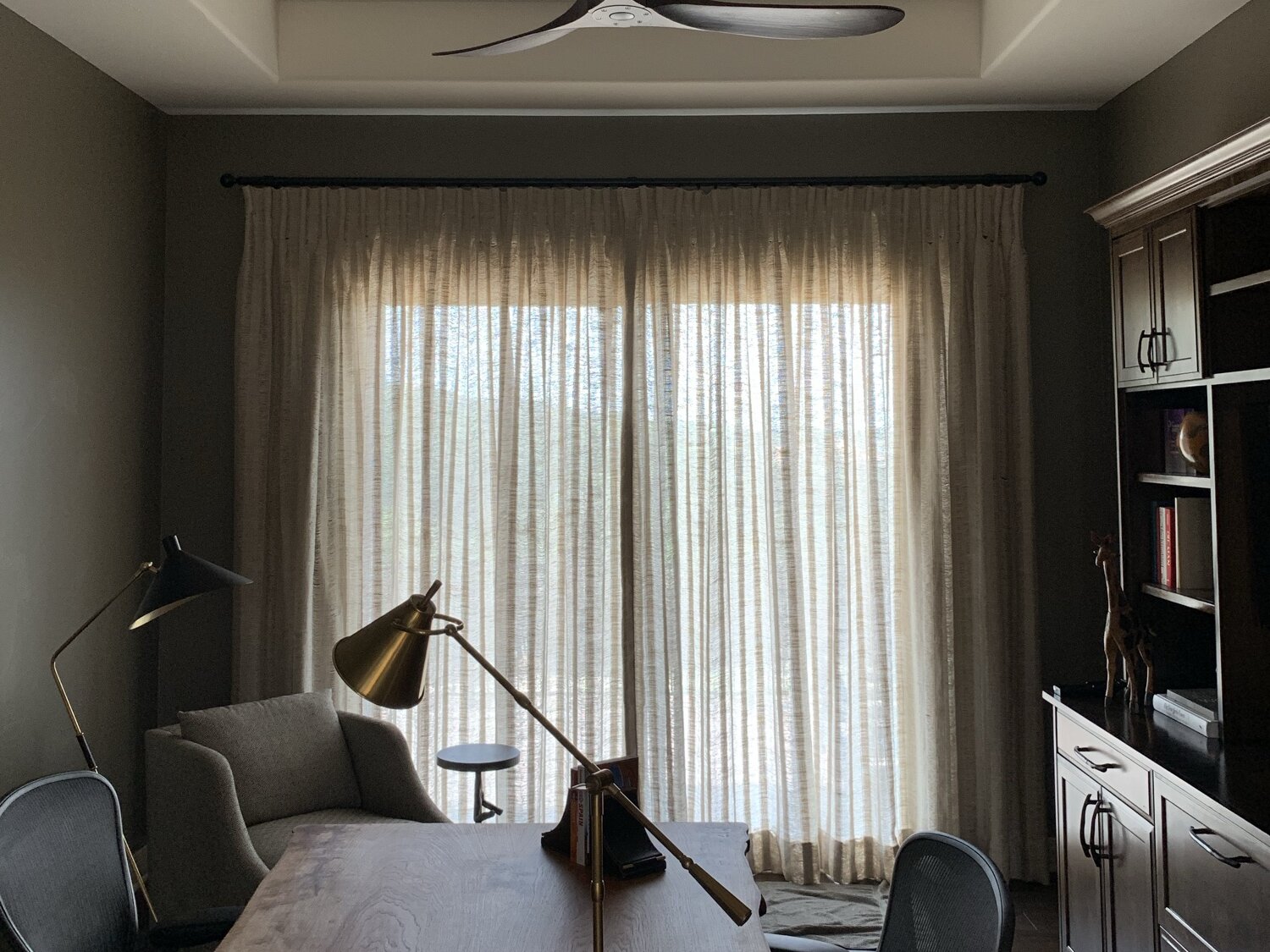 Afternoon light diffused through sheer drapes in a quiet study with in-ceiling speakers