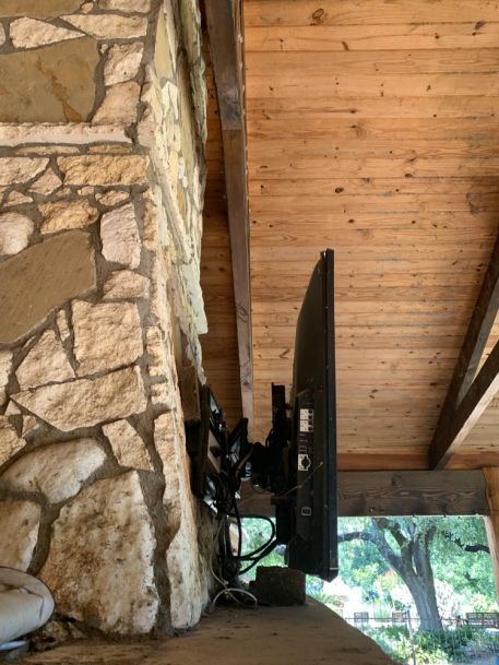 TV mounted to stone wall with wooden ceiling