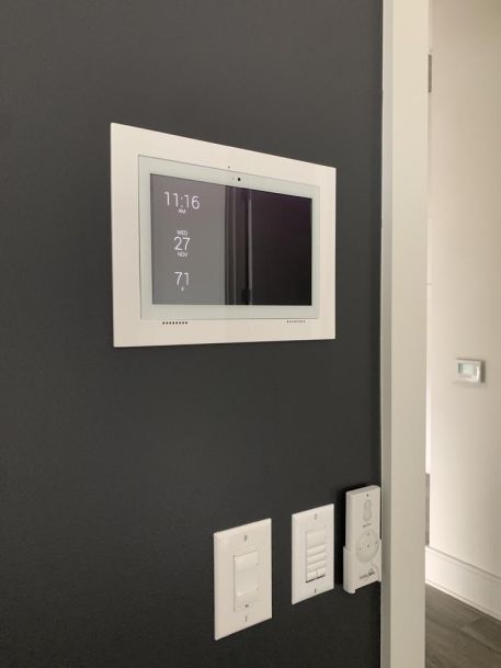touch panel on black wall next to lighting switches