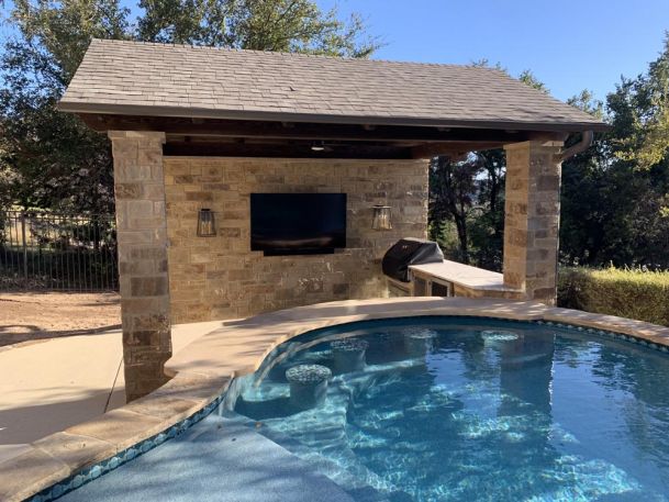 TV mounted on stone wall by pool